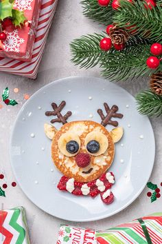 a plate topped with pancakes covered in frosting and reindeer face toppings next to christmas decorations