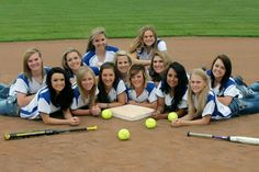 a group of young women sitting on top of a baseball field holding tennis balls and racquets