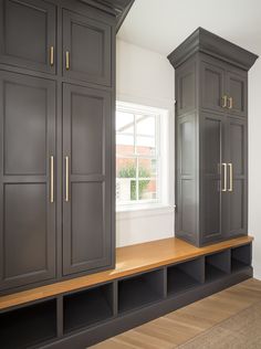 an empty room with gray cabinets and wood flooring