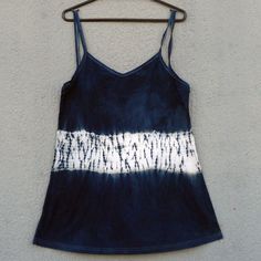 a blue and white tie dye tank top hanging on a metal rack against a wall