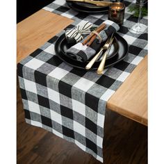 a black and white checkered table cloth with silverware on it is sitting on a wooden table