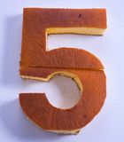 the number five is made out of orange frosting and sits on a white surface