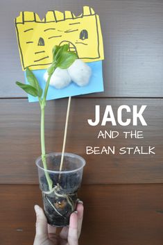 a person holding up a plant in front of a sign that says jack and the bean stalk