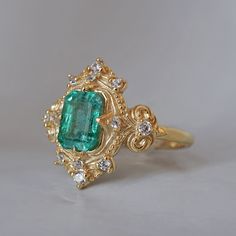 Read about our payment plans before proceeding. Palais d'Émeraude: A Parisian Royal Masterpiece Introducing the Emerald Palais Diamond Ring, an exquisite ring that captures Parisian elegance and sophistication. At its center, a lush emerald evokes the opulence of royal gardens. Inspired by Parisian palaces, this ring features delicate curves and ornate details that wrap around the vibrant emerald. The meticulous craftsmanship makes it a true masterpiece, fit for royalty. "Palais" translates to "Palace," reflecting the regal beauty and timeless charm of this piece. The emerald symbolizes rebirth, love, and fortune, elegantly embraced by the intricate band. All orders come in our Tippy Taste ring box. This ring is handmade and designed in NYC. 14K or 18K solid gold Natural emerald-cut emeral Parisian Elegance, Royal Garden, Fancy Rings, Jewelry Lookbook, Jewelry Inspo, Natural Emerald, Ring Box, Emerald Cut, Fashion Rings