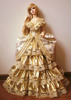 a barbie doll dressed in gold and white with long blonde hair wearing a golden dress