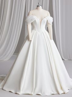 a white wedding dress on display in front of curtains