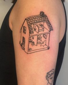 a woman's arm with a small tattoo of a house and cats on it