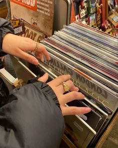 two hands reaching for records in a record store