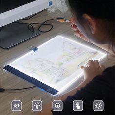 a woman is drawing on a light box