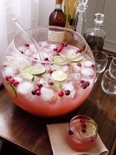 a pitcher filled with ice and cranberries on top of a table next to glasses