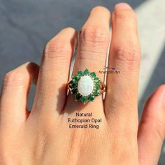 Natural Emerald Opal Ring For Women, Real Opal Ring For Women, Opal Cluster Ring With Emerald, White Opal Gemstone Ring, Opal Halo Ring Gift Vintage & Feminine White Opal & Emerald Floral Ring- petite & beautiful. A delightful & feminine 14ct gold Plated over 925 Silver white opal and emerald cluster ring, featuring a cabochon oval opal surrounded by a halo of round cut emeralds in this traditionally classic style. A raised claw setting completes the style of this elegant ring. 𝐒𝐩𝐞𝐜𝐢𝐟𝐢𝐜? Emerald And Opal Ring, White Gemstone Rings For May Birthstone, Oval Natural Stones Jewelry For Wedding, White Oval Emerald Ring For Gift, Elegant Opal Ring With Natural Stones For Anniversary, White Emerald Ring Jewelry, Round Emerald Ring With Natural Stones For Anniversary, Oval Cabochon Emerald Wedding Jewelry, Wedding Emerald Jewelry Oval Cabochon