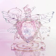 an angel figurine is sitting on top of a glass stand with its wings spread out