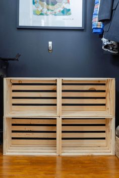 a wooden crate sitting on top of a hard wood floor next to a framed painting