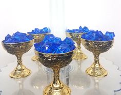 four gold goblets with blue glass in them