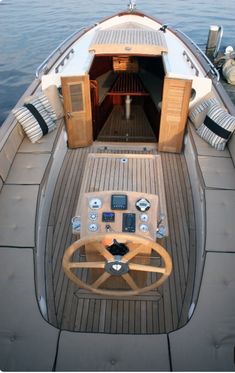 the inside of a small boat with its steering wheel and cockpit area open on water