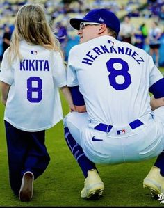 a couple of people that are sitting on the ground in baseball uniforms at a game