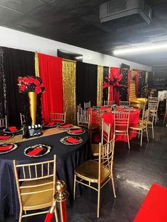 a banquet room set up with black and gold decor, red tablecloths and chairs