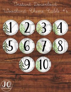 the woodland theme table numbers are displayed on a wooden surface with white and green leaves