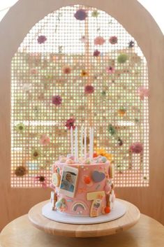 a pink cake sitting on top of a wooden table next to a window covered in flowers