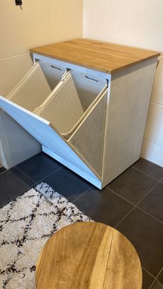 a kitchen area with a counter, stool and trash can on the floor next to a rug