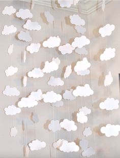 a mobile with clouds hanging from it's sides in front of a white wall