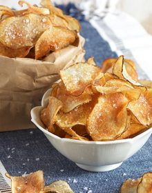 small bowls filled with potato chips on top of a blue table cloth next to a brown paper bag