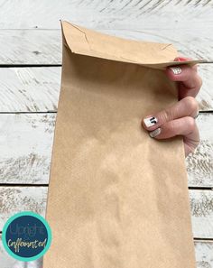 a person holding a brown paper bag with white writing on it