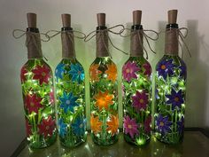 four glass bottles with lights in them are sitting on a table