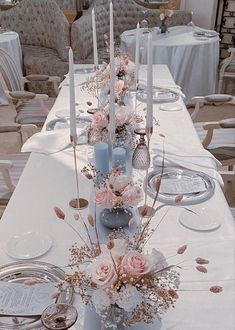 the table is set with candles, flowers and vases for an elegant dinner party