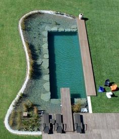 an aerial view of a swimming pool in the middle of a grassy area with two people laying on it