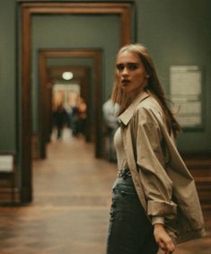 a woman is standing in an art museum with her hand on her hip and looking at the camera