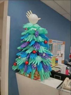 a decorated christmas tree in an office cubicle with blue and green gloves on it