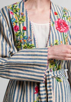 a woman wearing a blue and white striped cardigan with flowers on the sleeves,