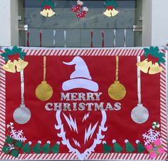 a red and white christmas sign hanging from the side of a building with decorations on it