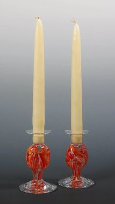 two candles sitting on top of each other in front of a gray background and one is red