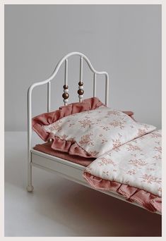 a small white bed with pink and white sheets