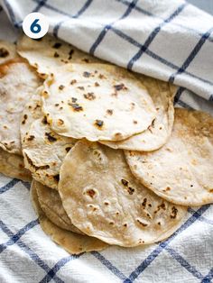 a pile of tortillas sitting on top of a blue and white checkered cloth