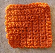 an orange crocheted square on the ground