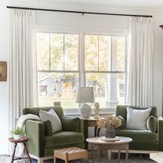 a living room with two green chairs and a coffee table in front of a window