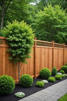 a wooden fence surrounded by shrubbery and black mulch