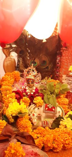 an elaborate arrangement of flowers and balloons with a mask on it's head in the background