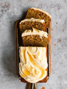 two slices of carrot bread with cream cheese frosting on top, sitting on a cooling rack