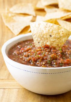 a white bowl filled with salsa and tortilla chips on top of a wooden table