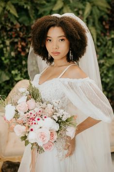 a woman in a wedding dress holding a bouquet with flowers on her shoulder and veil over her head