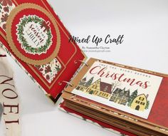 an open christmas card book on top of a white table with red and green paper