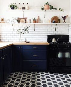 a black stove top oven sitting inside of a kitchen next to a white tiled wall