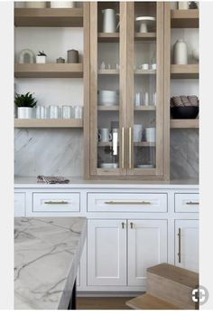 a kitchen with marble counter tops and wooden cabinets in the center, along with white cupboards