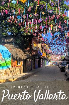 the street is lined with colorful kites hanging from it's ceiling and there are cars parked on the side of the road