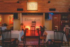 an empty restaurant with white tablecloths and wooden chairs in front of the door