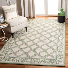 a green and white rug in a living room with a chair next to the window